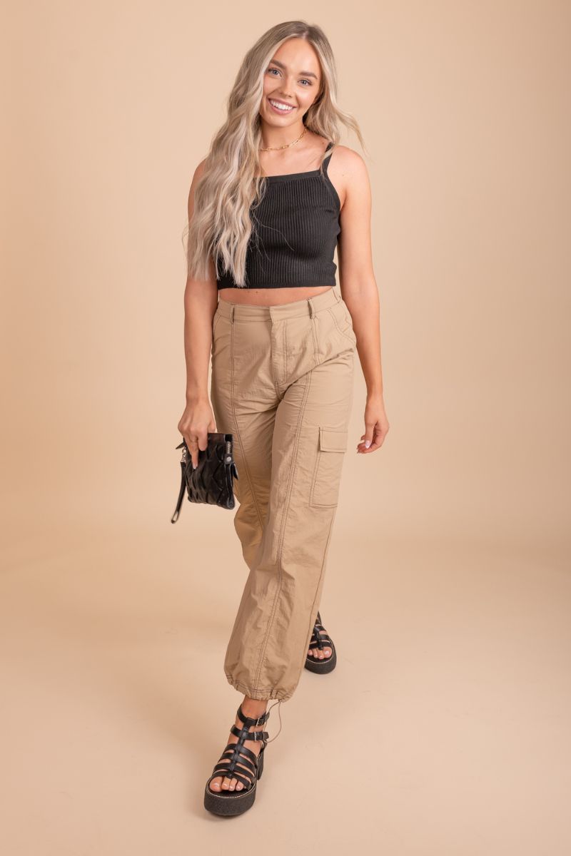 Image of a pair of tan cargo pants on a model in front of tan background. The pants have a relaxed fit with multiple pockets located on the sides of the legs. The fabric appears to be sturdy and textured, with a slightly faded look to it.