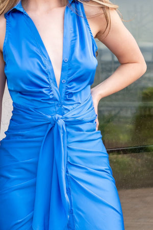 Model wearing a blue dress in front of a building.