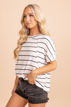 Image of a black and white top with a color block design. The top has a flattering and feminine cut and is made with soft and breathable fabric. The black and white color block design gives it a modern and sophisticated look. The top is shown on a model against a tan background.