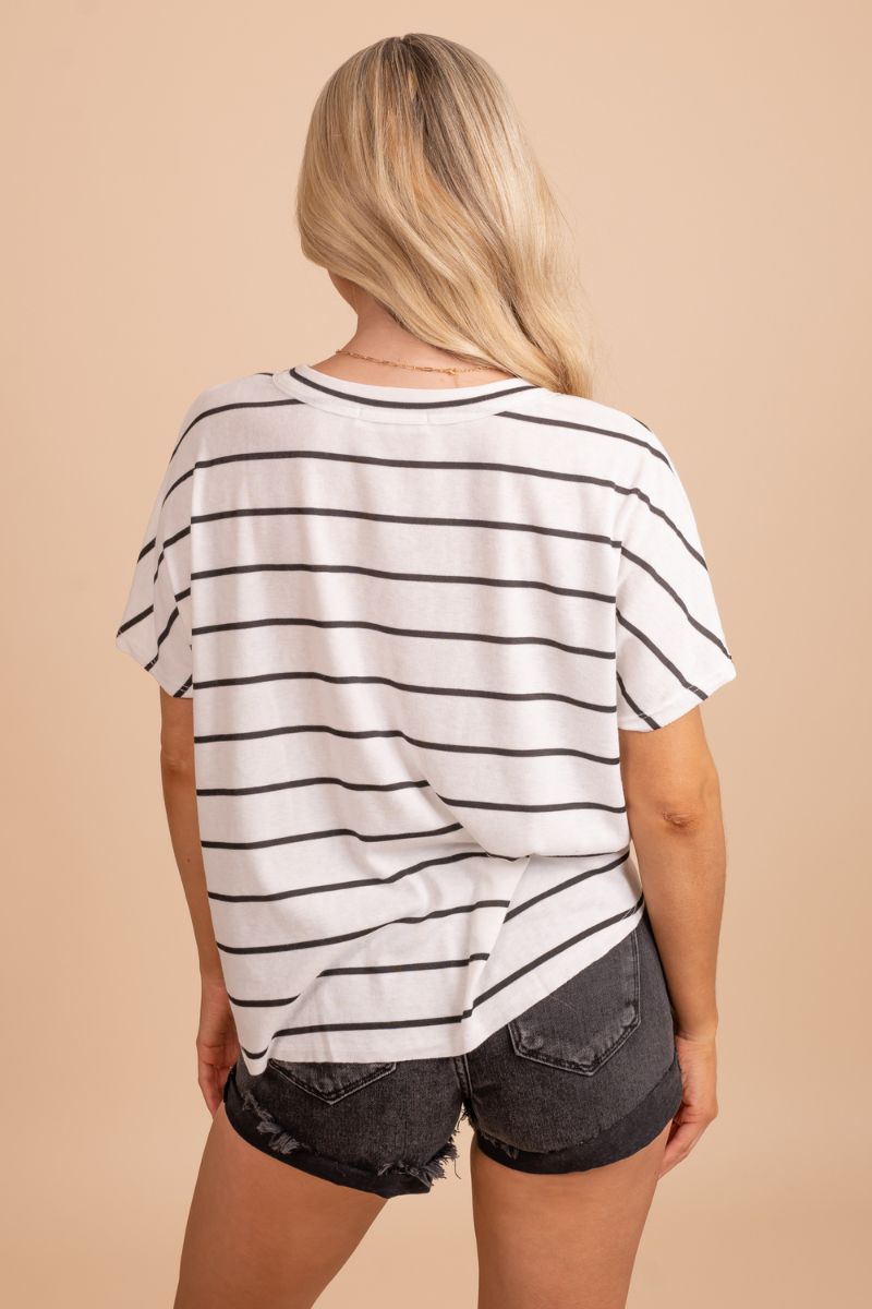 Image of a black and white top with a color block design. The top has a flattering and feminine cut and is made with soft and breathable fabric. The black and white color block design gives it a modern and sophisticated look. The top is shown on a model against a tan background.