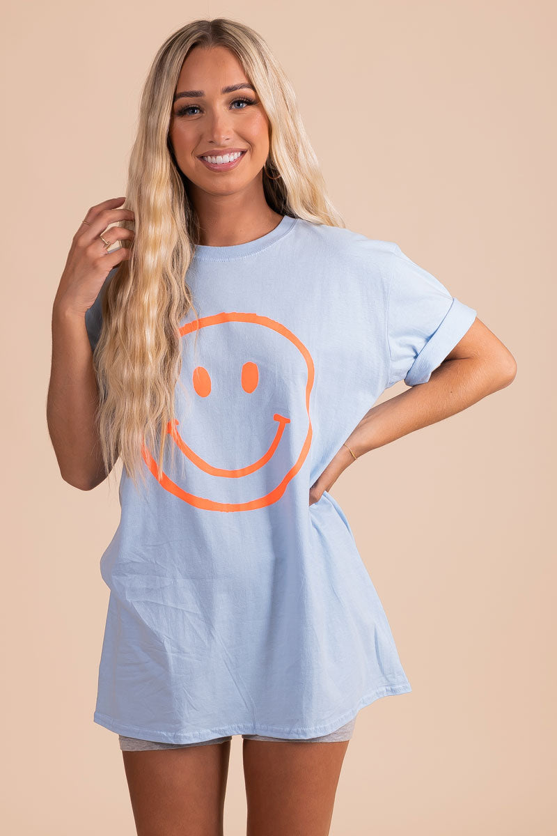 boutique light blue graphic tee with neon orange smiley face graphic